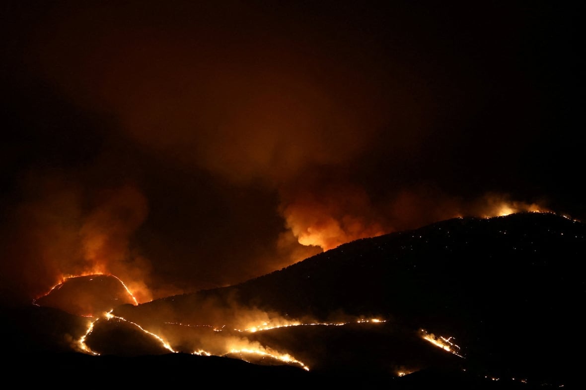 रात्रीच्या आकाशाच्या विरूद्ध डोंगराच्या प्रदेशात ऑरेंजेलची ज्योत आणि धूम्रपान