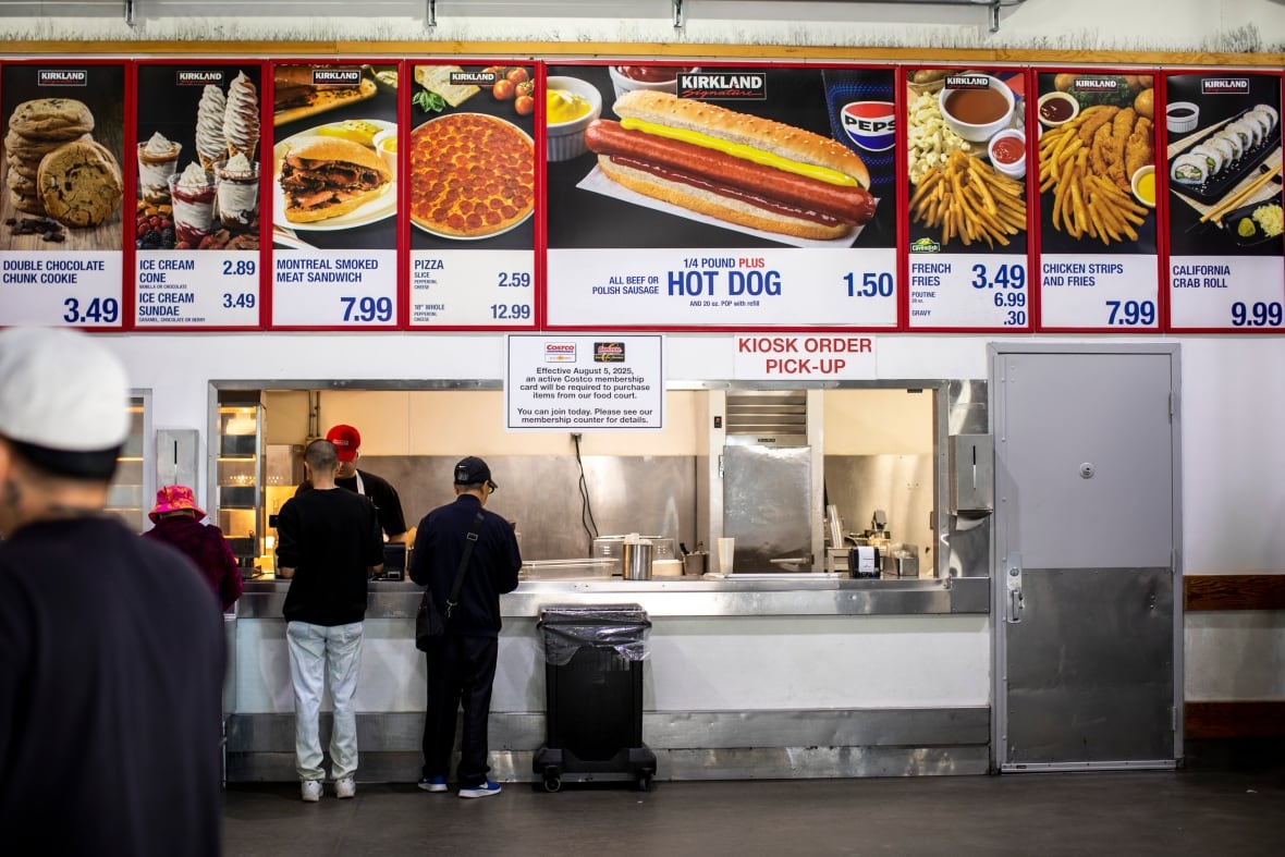 People stand in line at a food court advertising $1.50 hot dogs