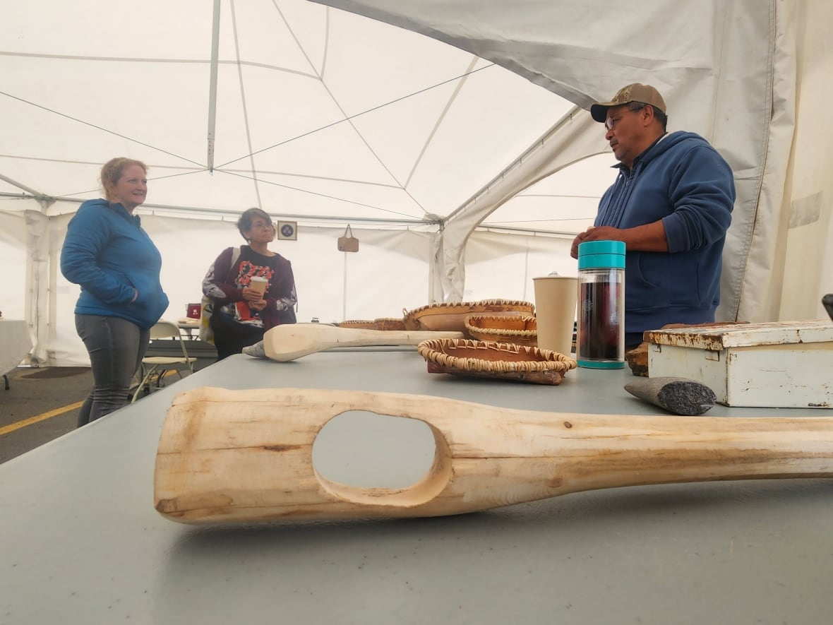 Artist Doug Smarch explains his art, and experiential archaeology, to visitors to his booth.