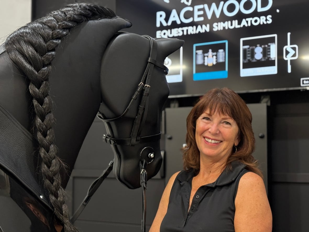 A woman smiles next to a mechanical horse