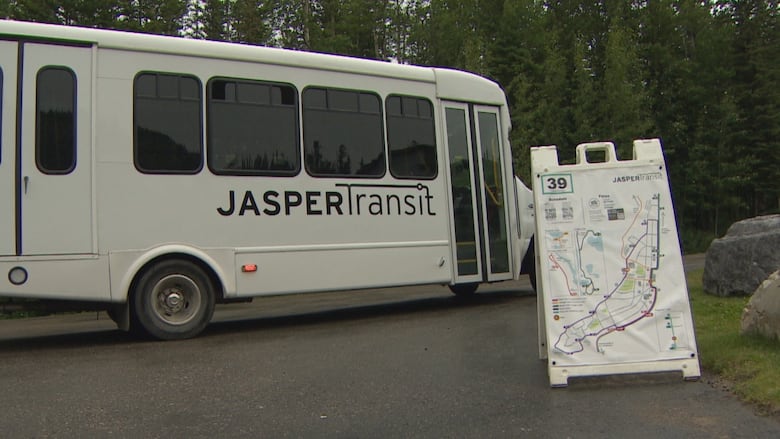 A small, beige commuter bus with "Jasper Transit" written on the side makes a brief stop at Folding Mountain before heading to Jasper on one of its five daily runs from Hinton.