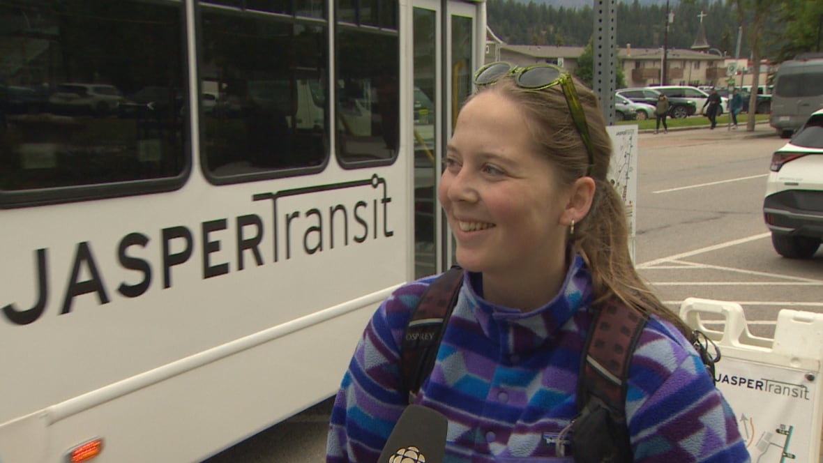 A woman from Denmark, wearing a purple patterned fleece jacket smiles as she speaks to CBC News at the Jasper Transit Hub.