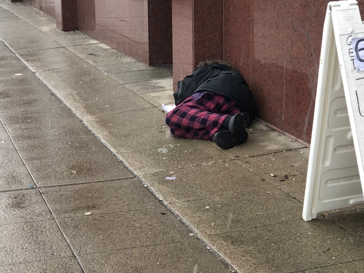 A homeless person sleeping on a sidewalk.