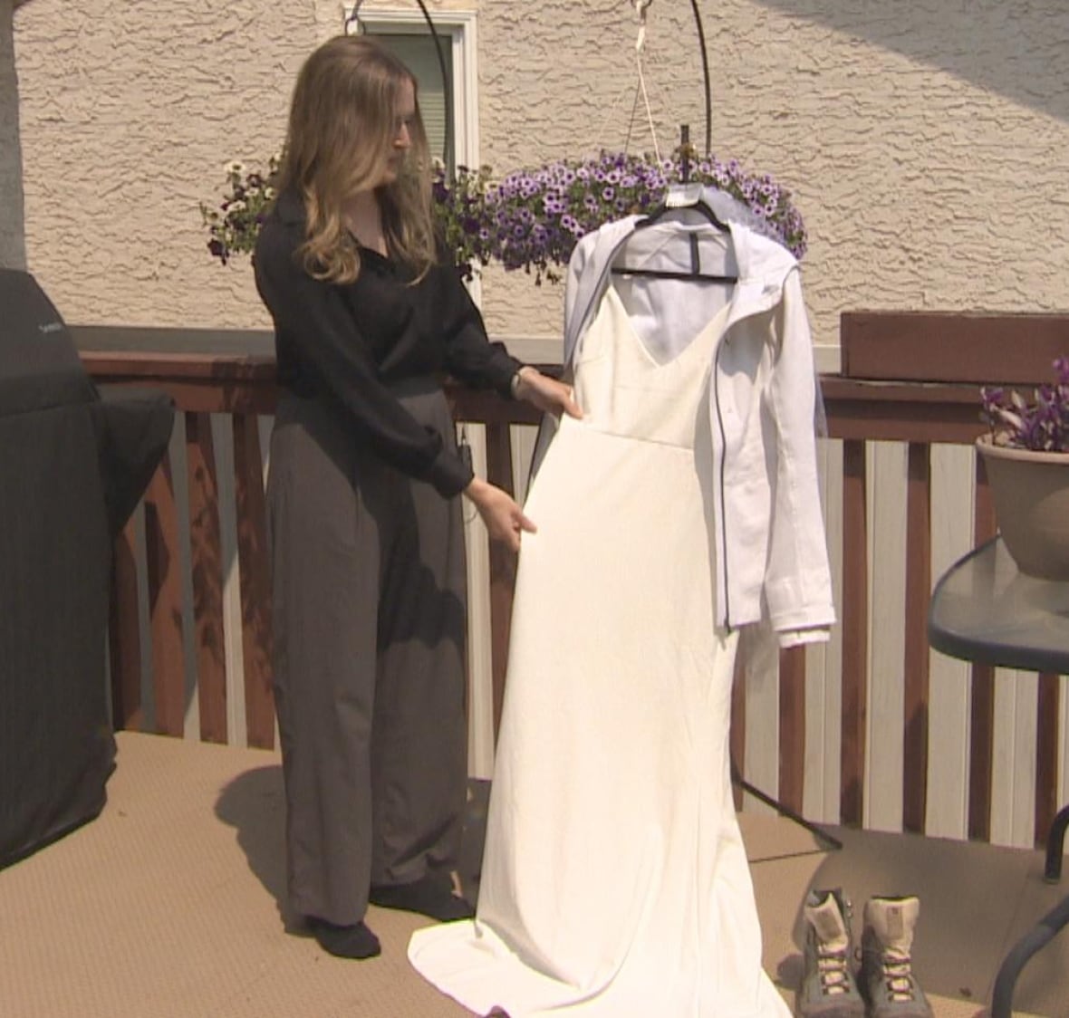 Kelsey Bone está parado en una cubierta de madera mientras muestra su vestido de novia blanco.