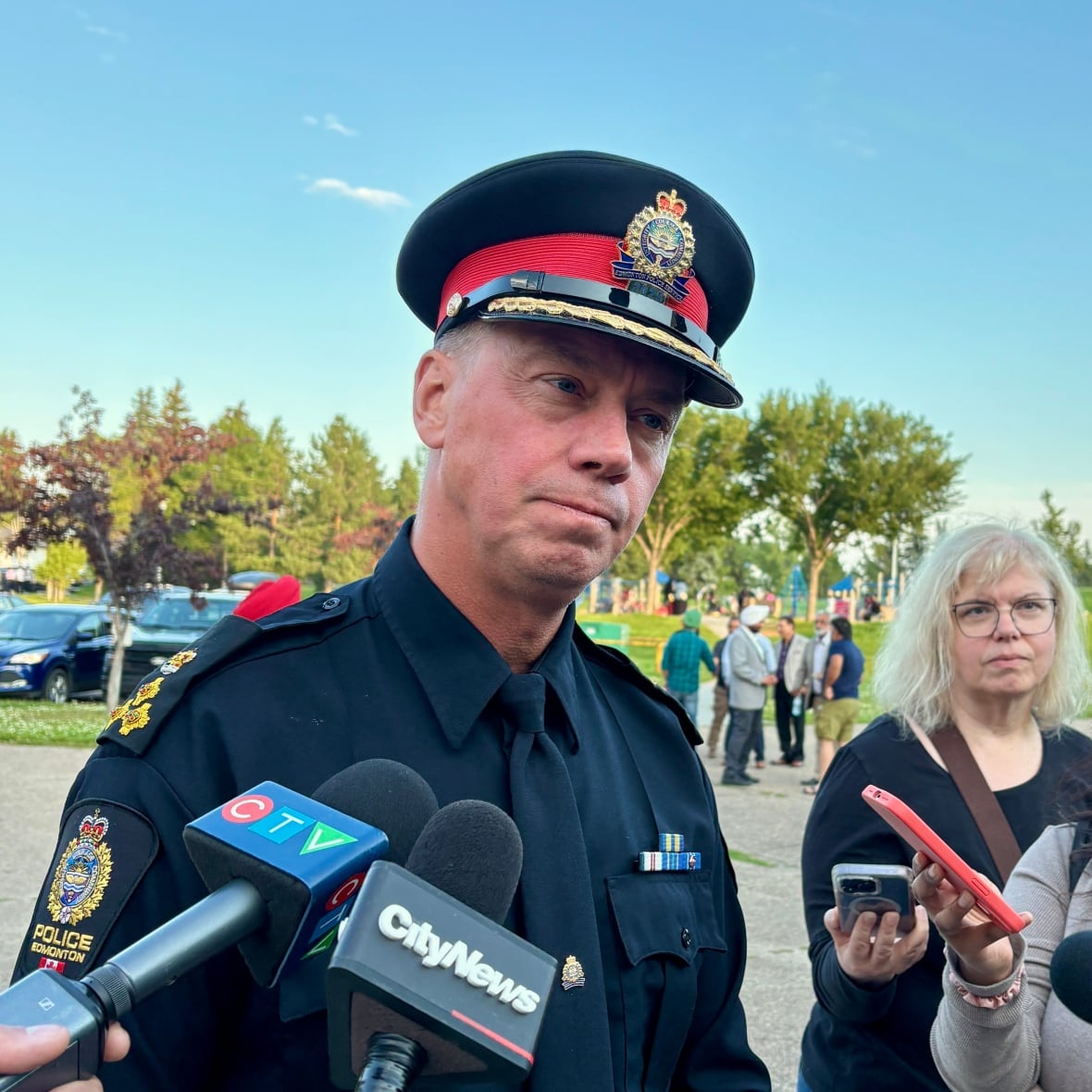 A police officer stands in front of reporters in a scrum.