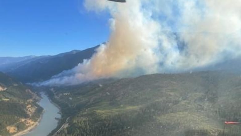 Smoke arises from a fire along a river.