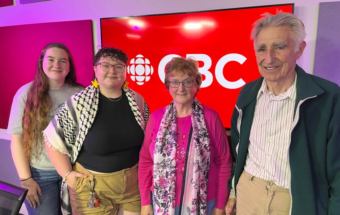 Four people are standing next to each other and smiling.