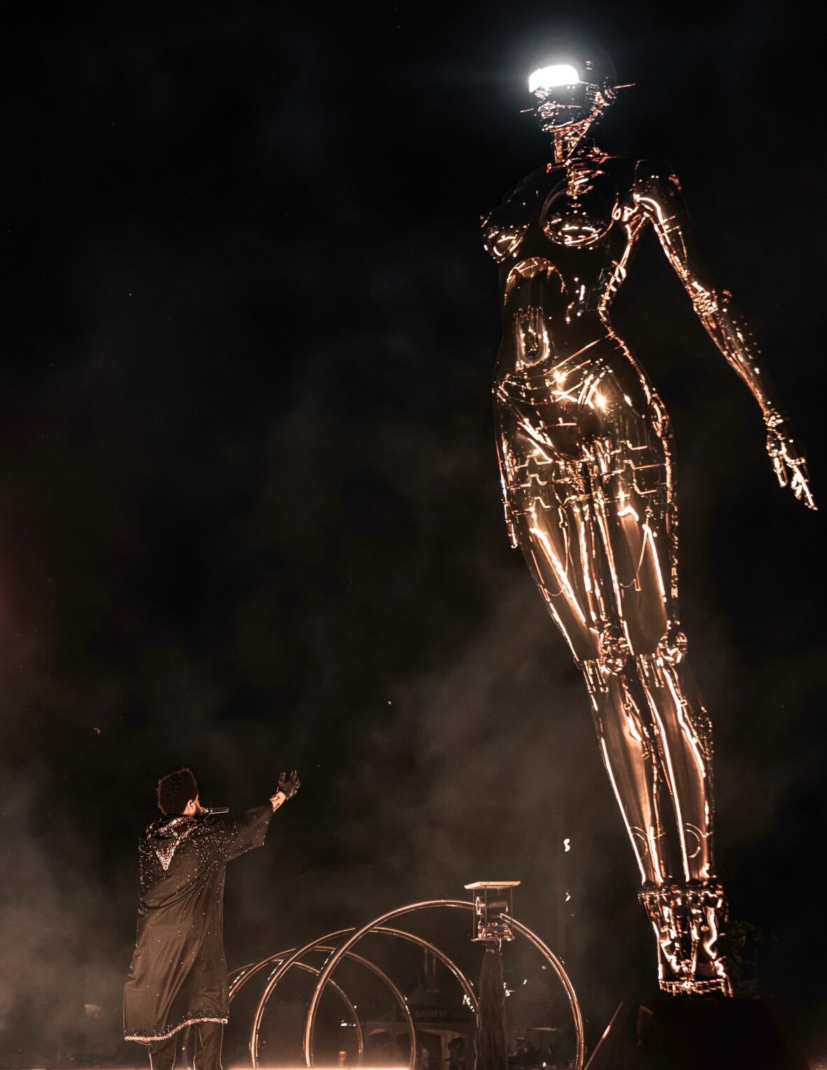 The Weeknd sings from below his golden statue. 