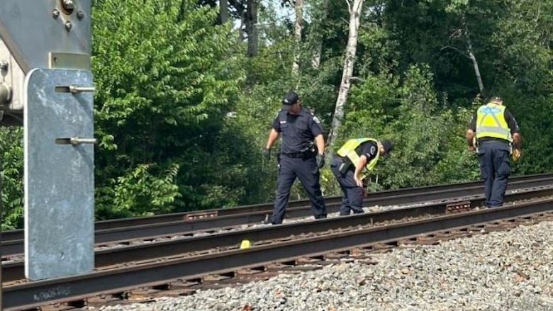 three people collect evidence from a train track