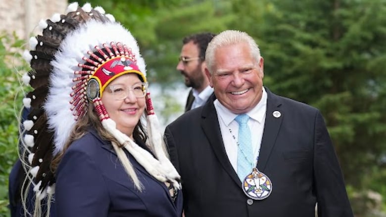 Woman in chiefs headdress and a man standing next to her