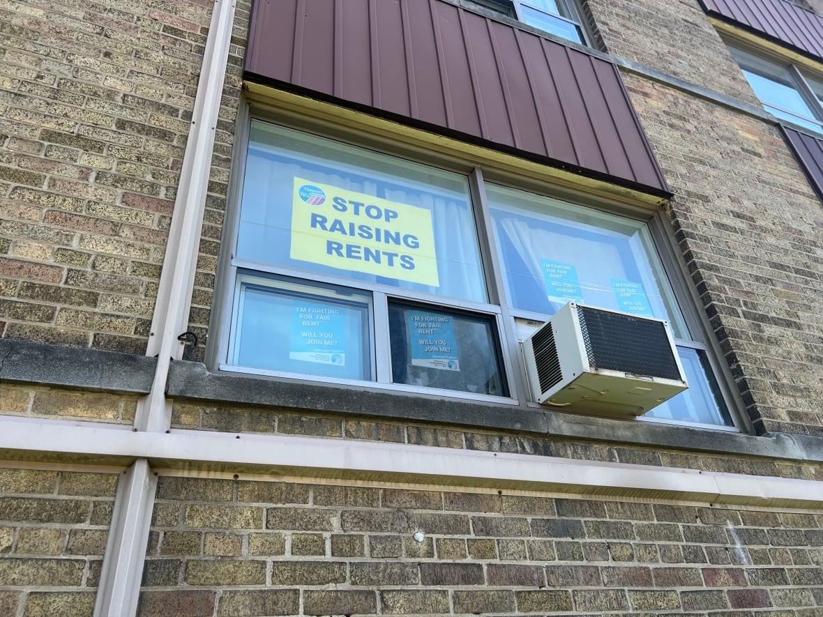 A photograph of a sign that says "Stop Raising Rents" in the window of a building on Clearview Heights.