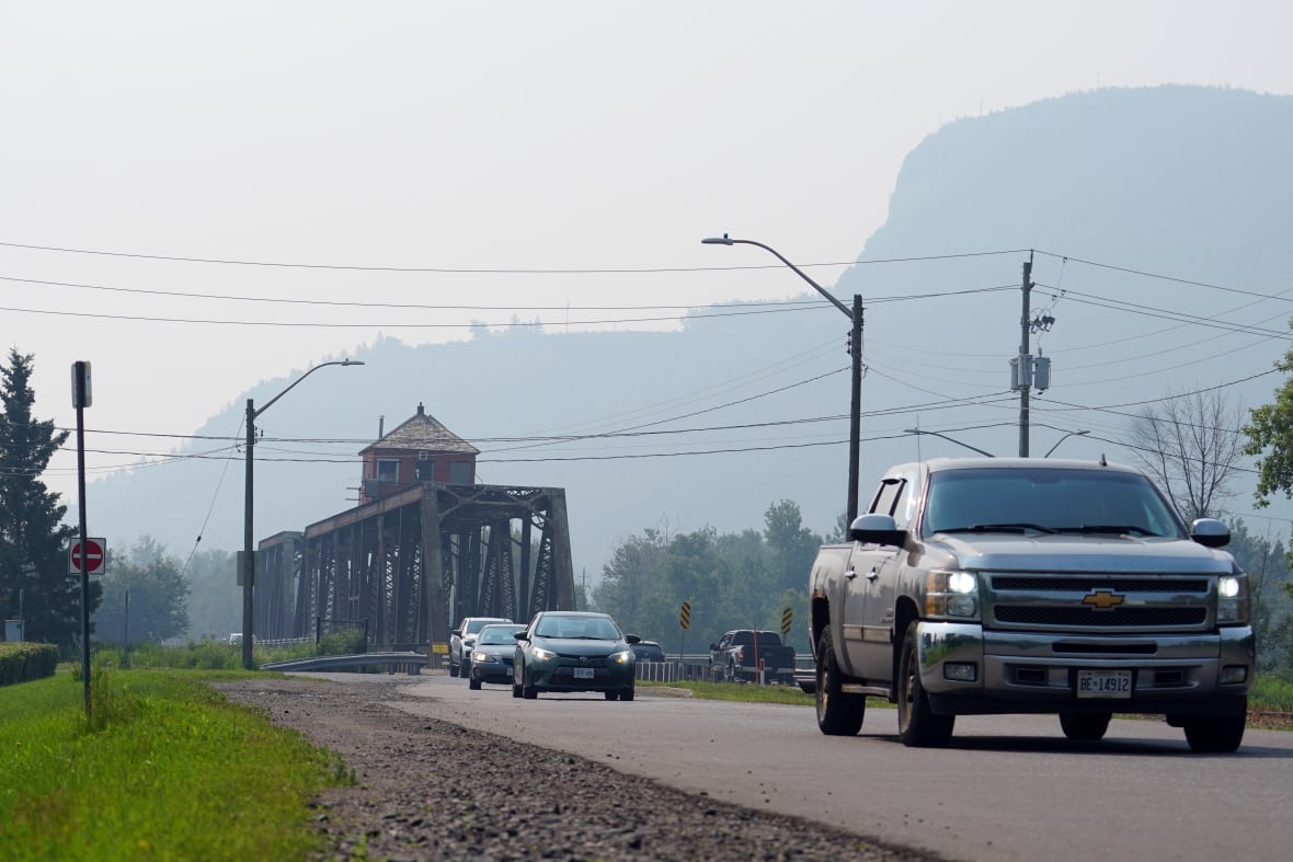 A hazy mountain is seen behind traffic driving over a bridge.