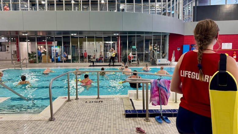 Picture of people doing class in pool with a lifeguard on duty.