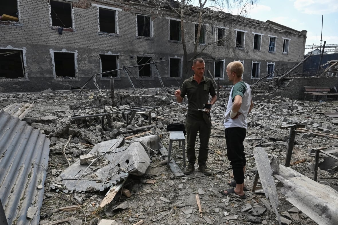 A soldier speaks with a prisoner at the site of the criminal colony of a Russian air strike, amid Russia's attack on Ukraine, in the Zaburisvia region, Ukraine, July 29, 2025. 