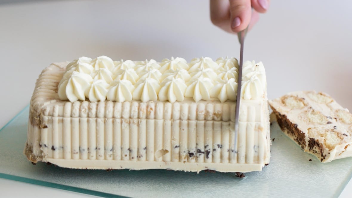 An ice cream cake being sliced.