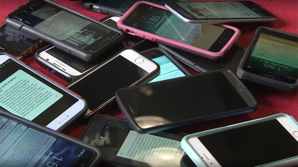 Several smartphones piled on a table.