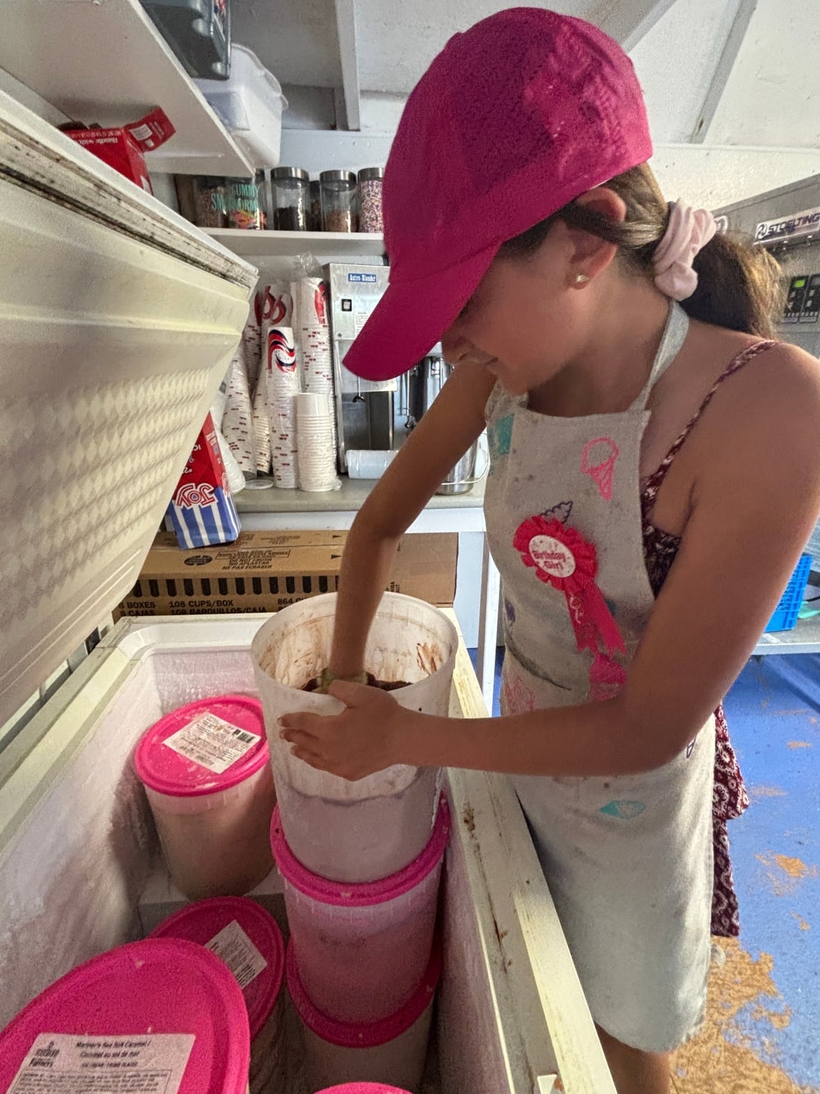 A girl in a pink hat schools ice cream.