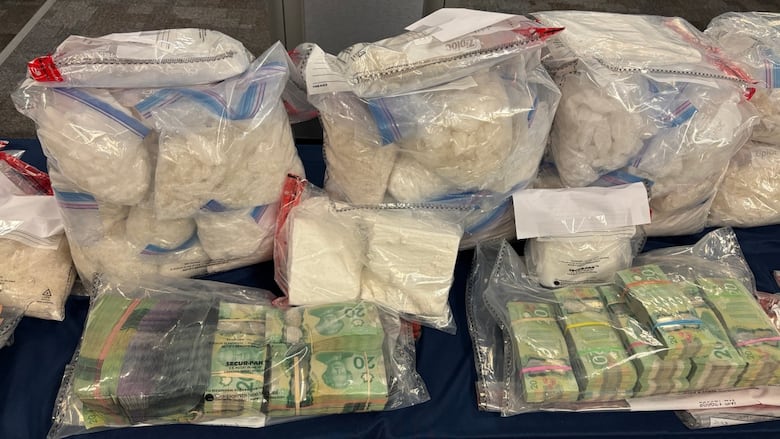A table with $20 banknotes and some sort of white chunks bagged in several transparent Ziplocs.