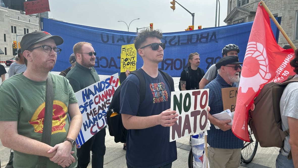 People carrying placards reading hands off Canada and no to NATO.