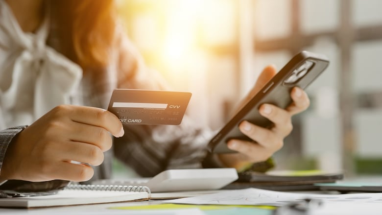 Person holds a credit card in one hand and phone in the other