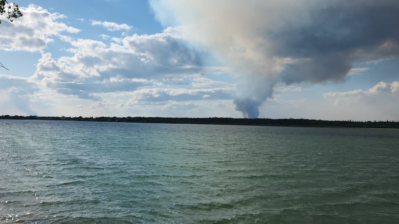 Smoke billowing from the other shore of a lake