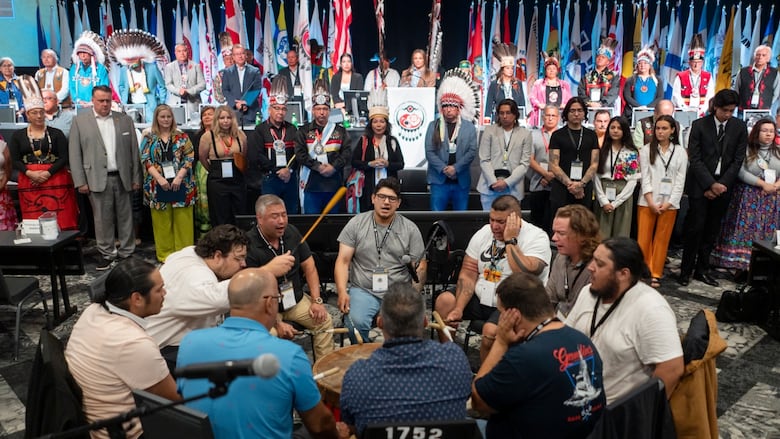 Group of people sit in circle playing a drum