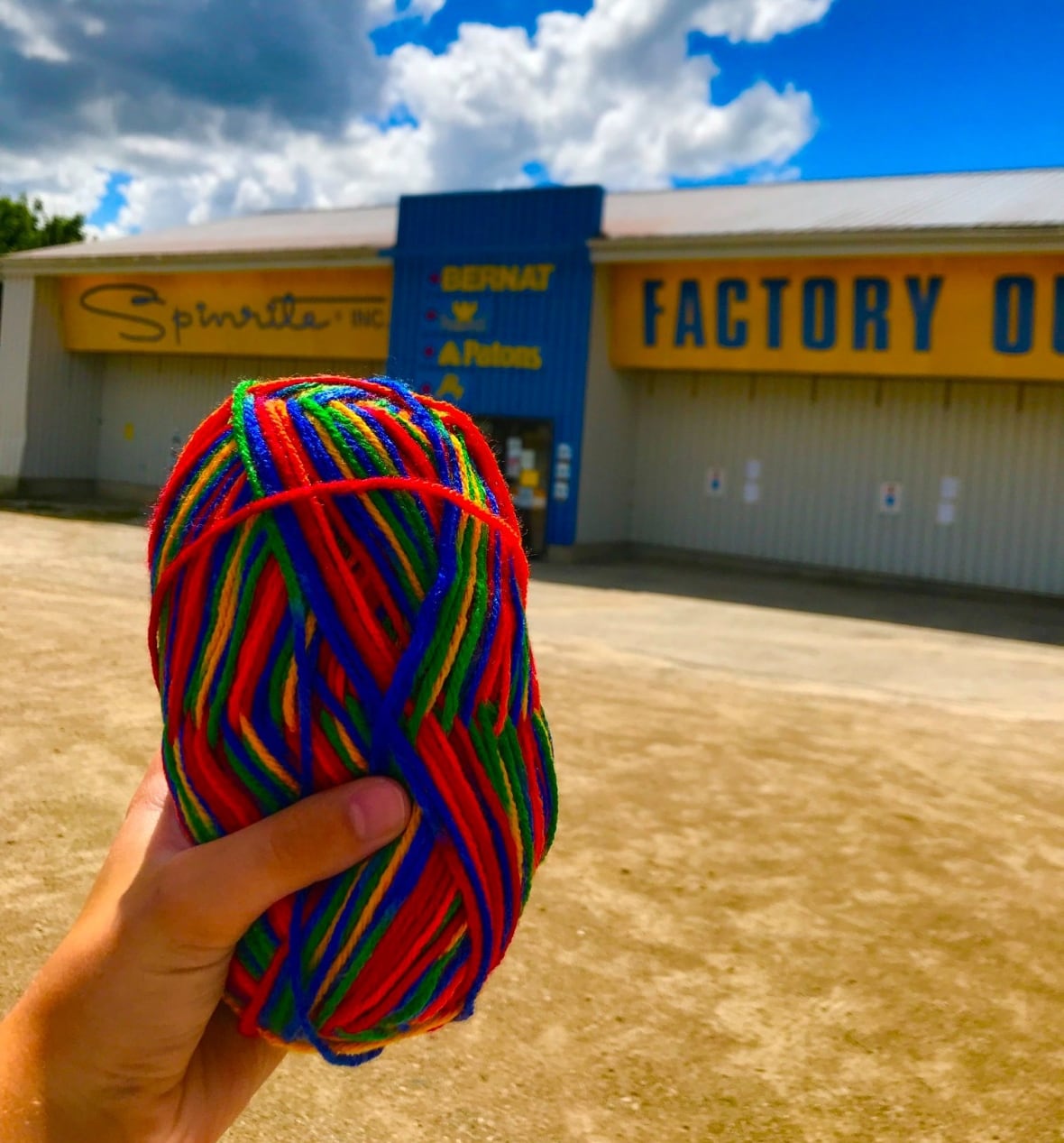 Rainbow yarn held up in front of a store