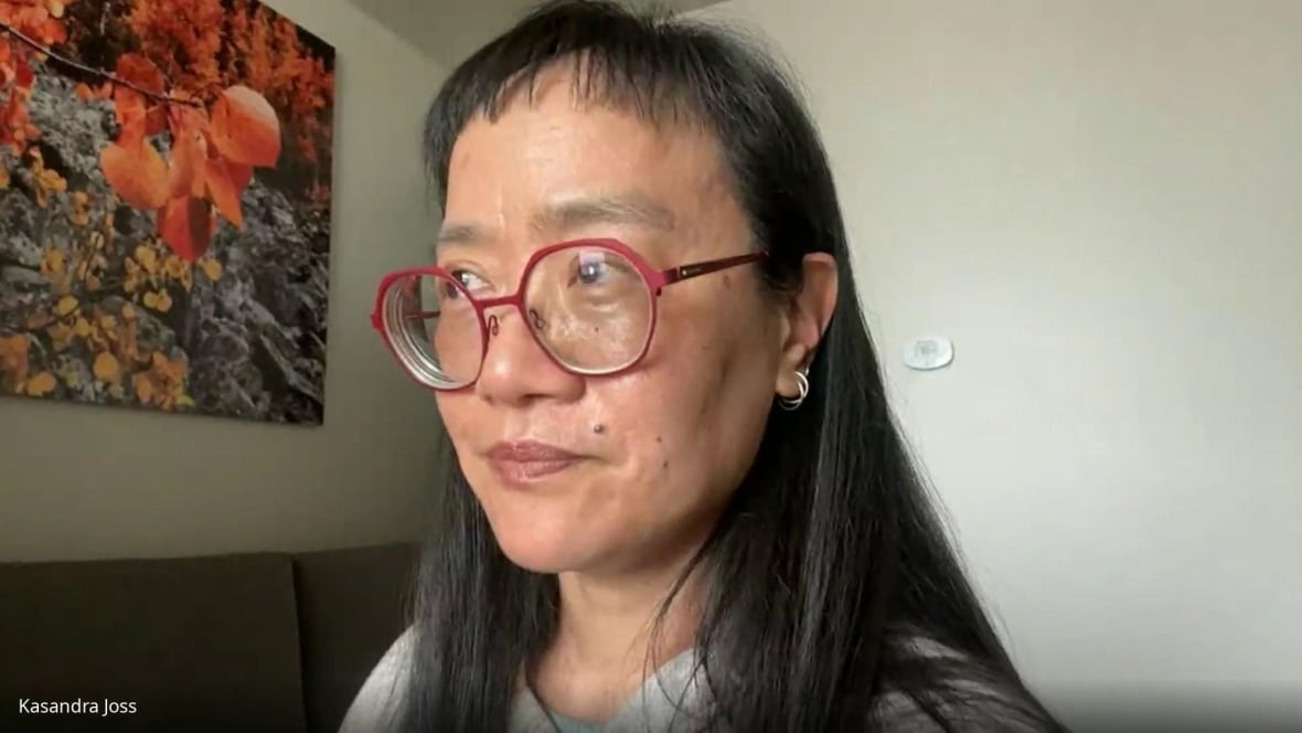 Dr. Kasandra Joss speaks to a reporter in a Zoom call. She is wearing pink-rimmed glasses and has black hair.