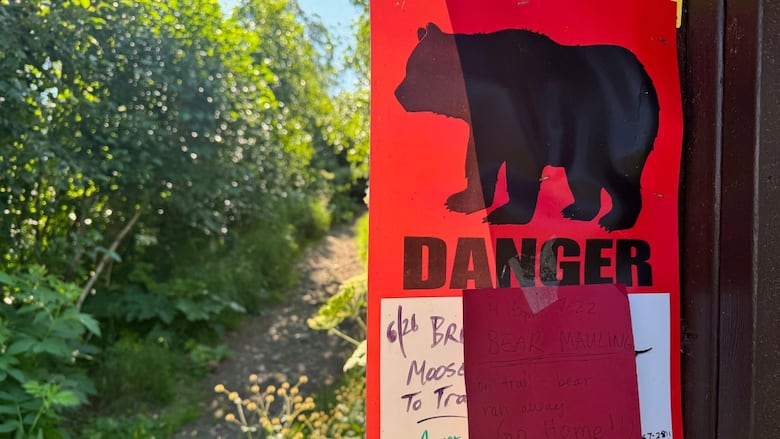 A sign posted on a pole warns of a bear.