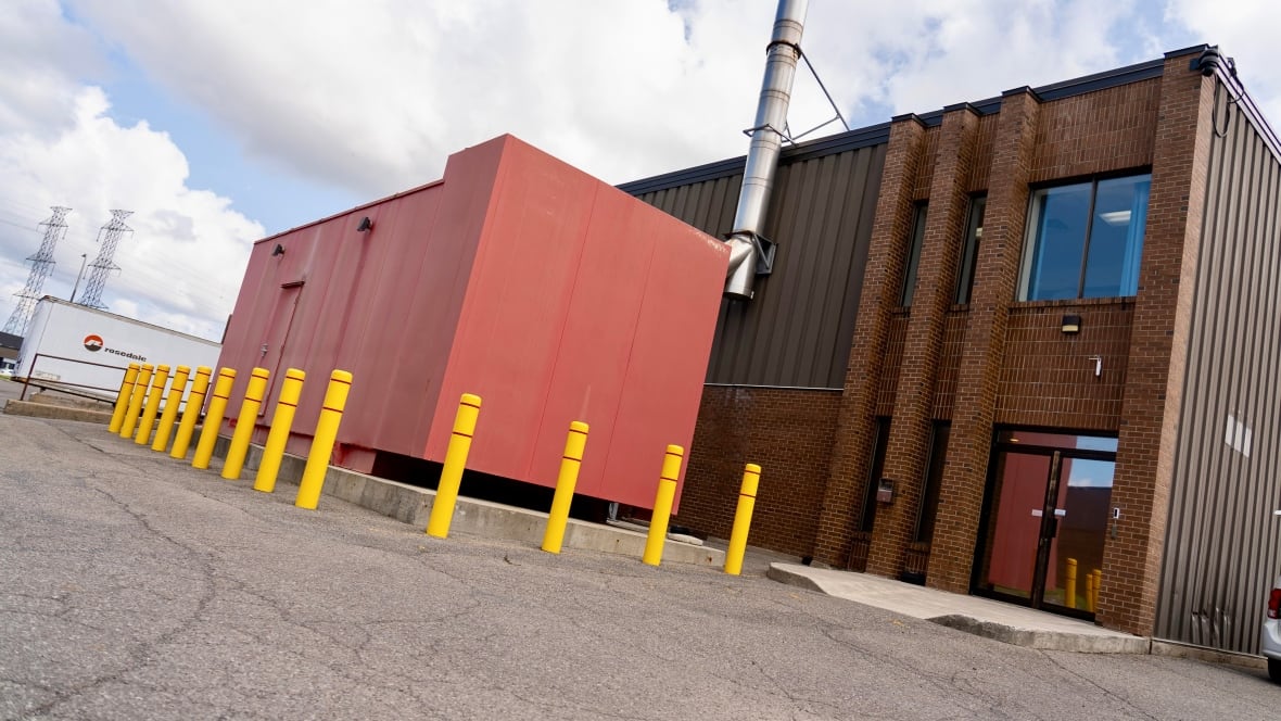 A big red generator sits beside a brick building