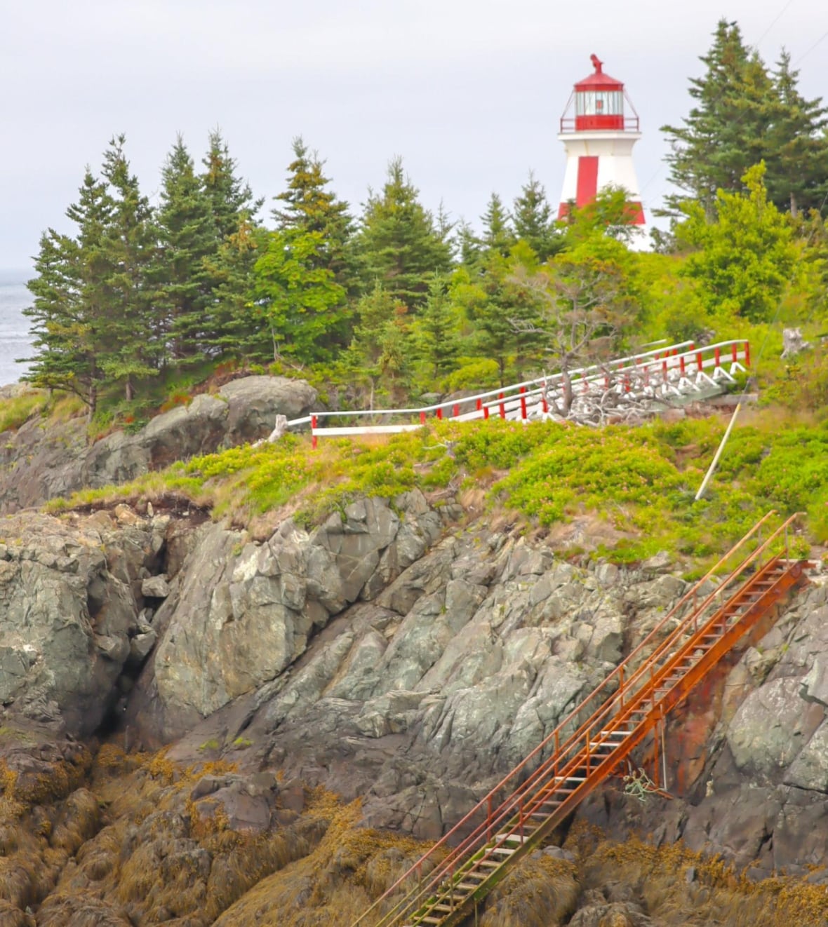 A lighthouse with sets of stairs leading from the beach