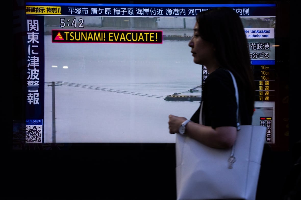 A woman walks past a TV screen