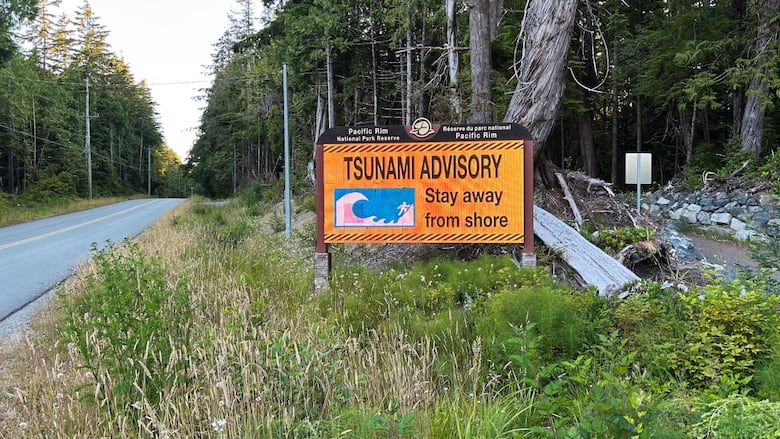 A sign by a wooded roadside says tsunami warning