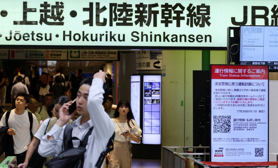 A man is displayed on the phone inside a train station, with a crowd of other people behind it and teach the Japanese around it. 