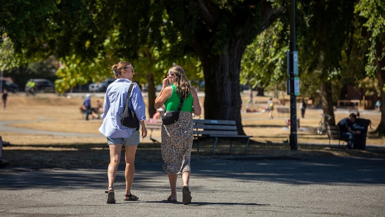 Two women walk along a beachfront path.