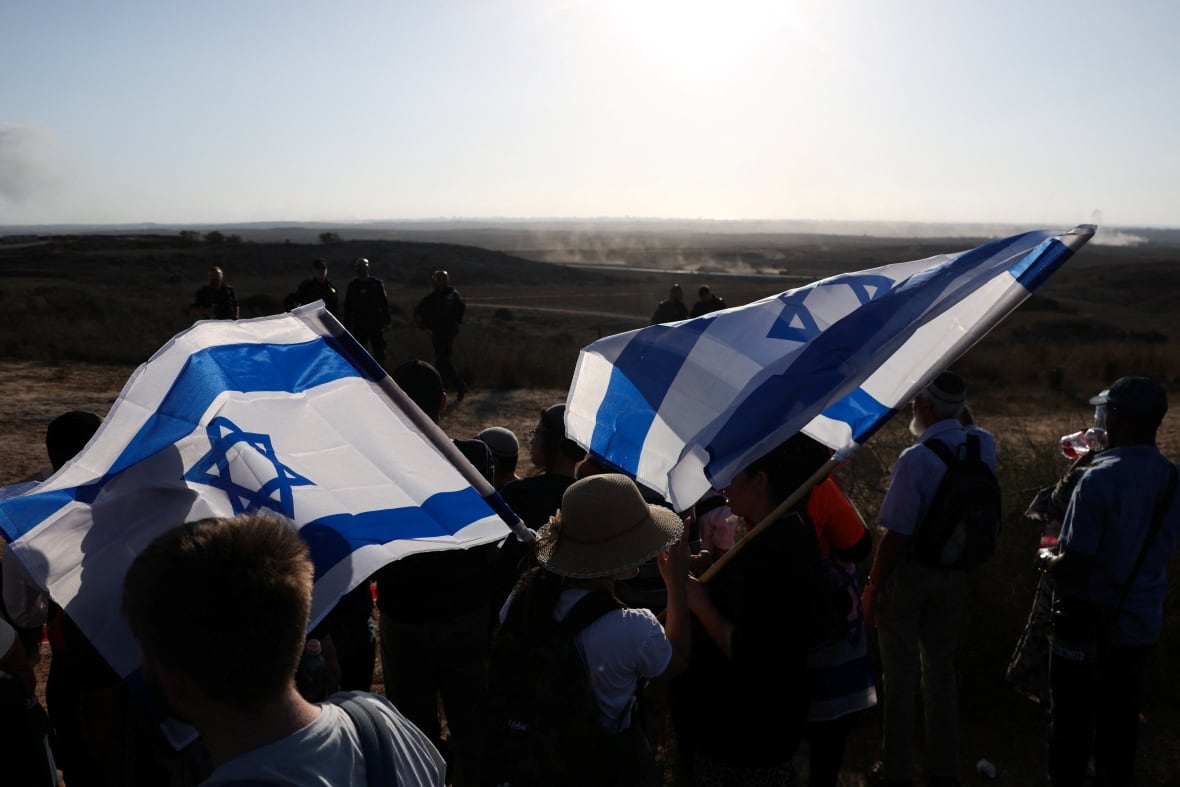 People waving Israeli flags on the borders of Israel Gaza.