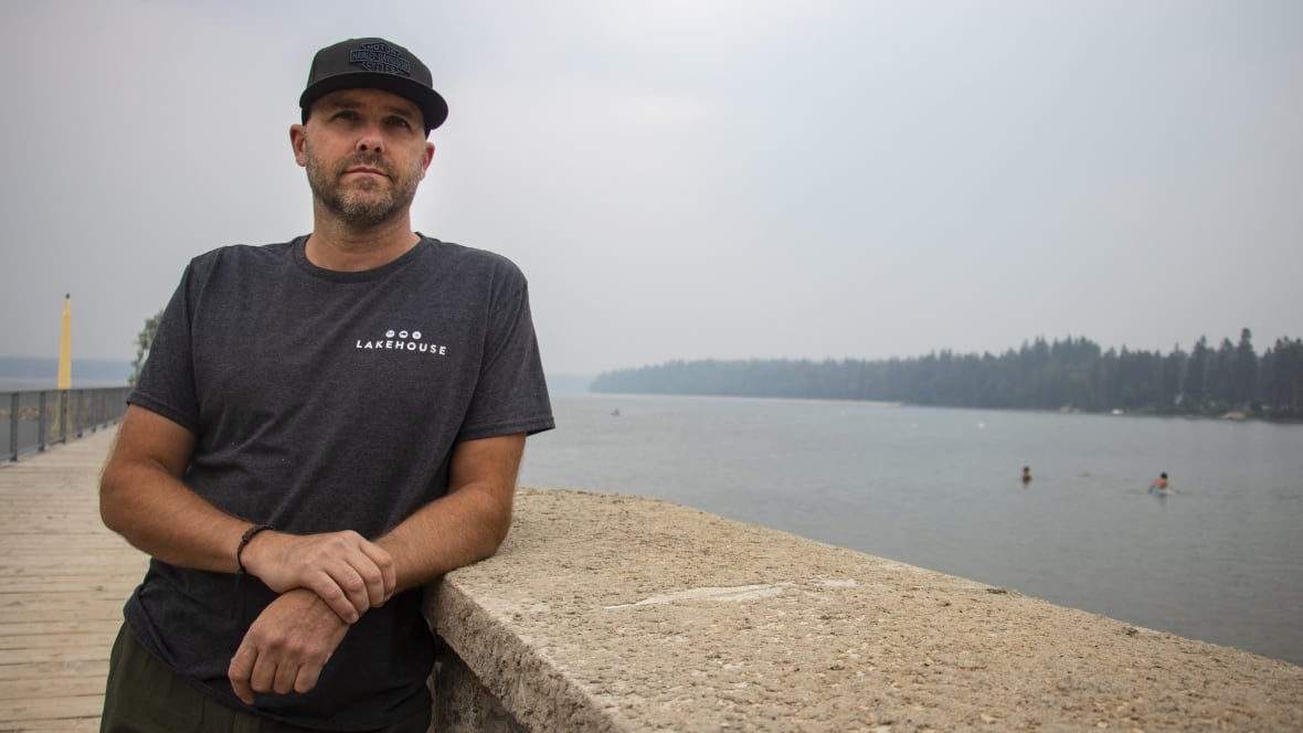 A man stands by a lake.