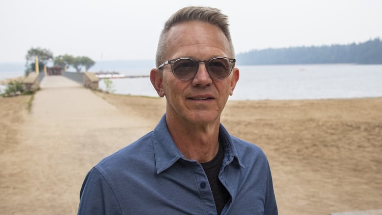 A man stands by a lake.
