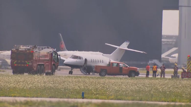 Plane at airport surrounded by emergency services