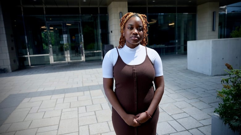 A woman stands in front of the entrance to an apartment building