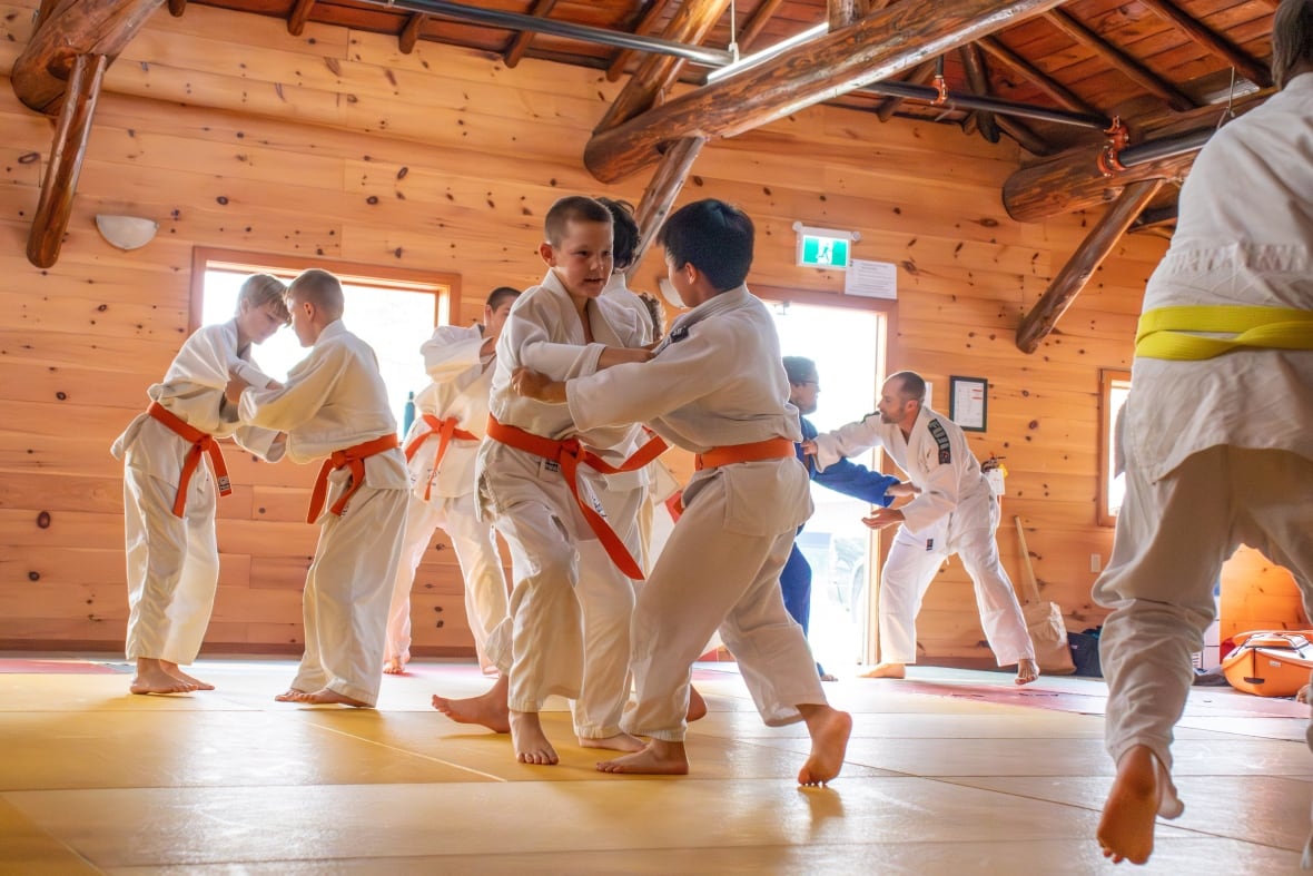 People are seen practicing judo in a wooden building.
