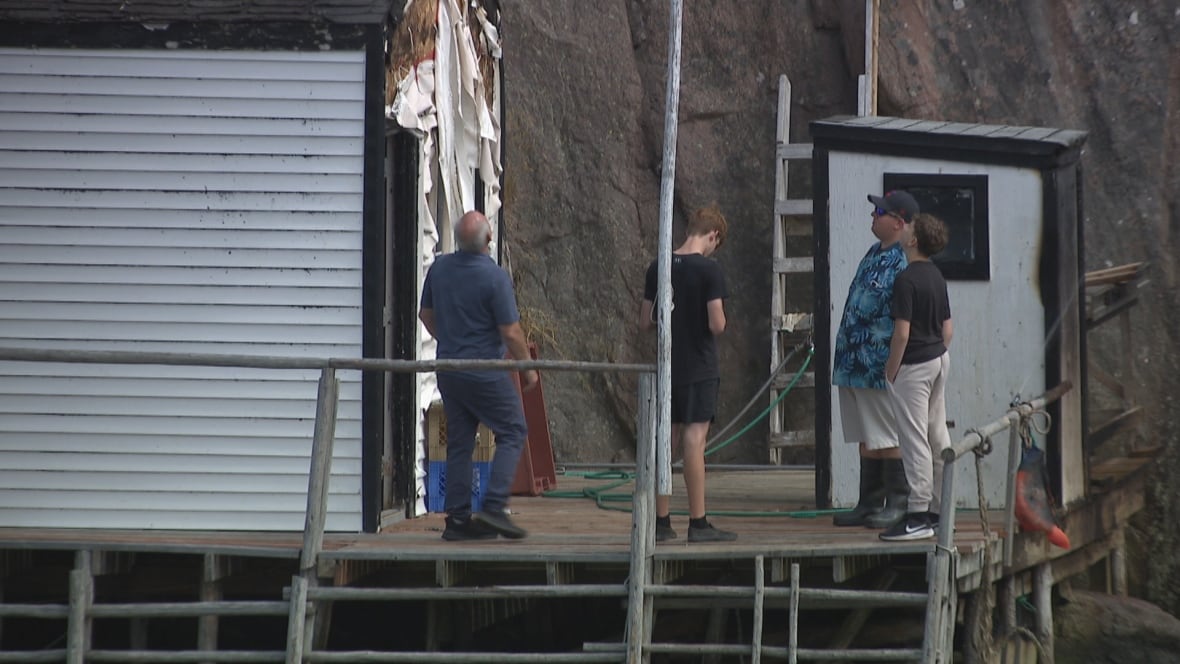 Men looking up at a burned fishing stage