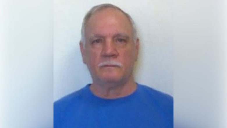 Man with short white hair, white mustache in blue t-shirt