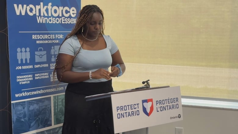 A young woman stands at a podium addressing an audience.