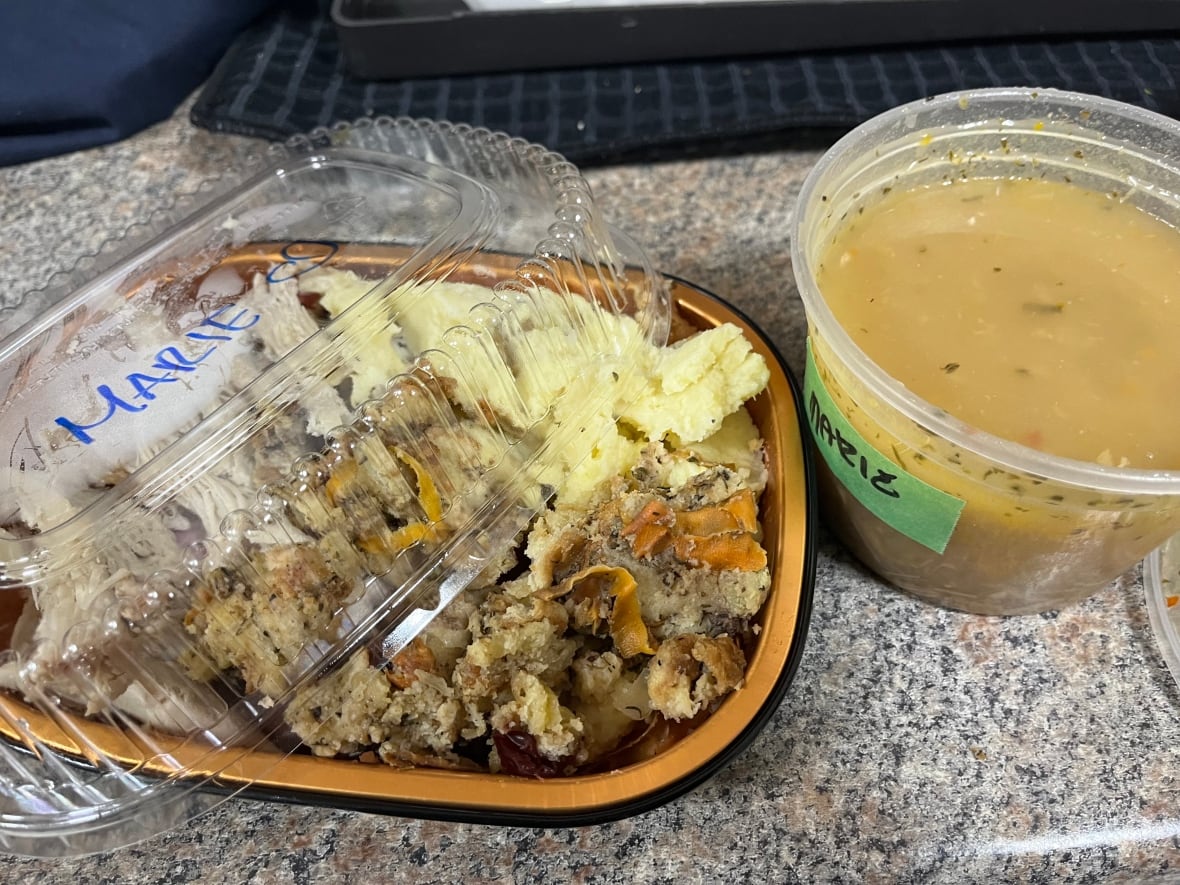 Two plastic containers labelled ‘Marie.’ One of them holds a soup and the other has Thanksgiving dinner leftovers of mashed potatoes, turkey and stuffing.