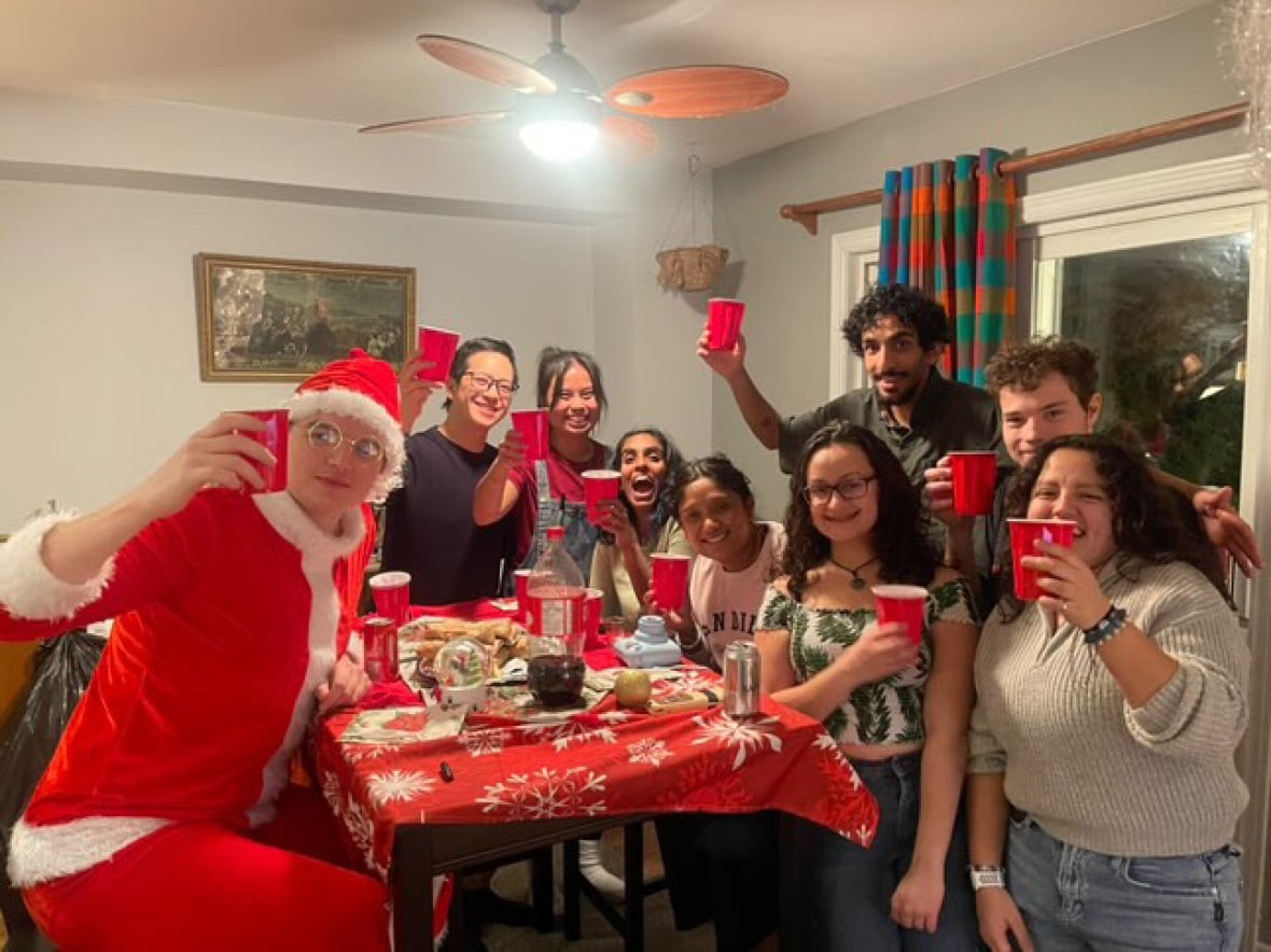 A group of smiling people toast with red cups.
