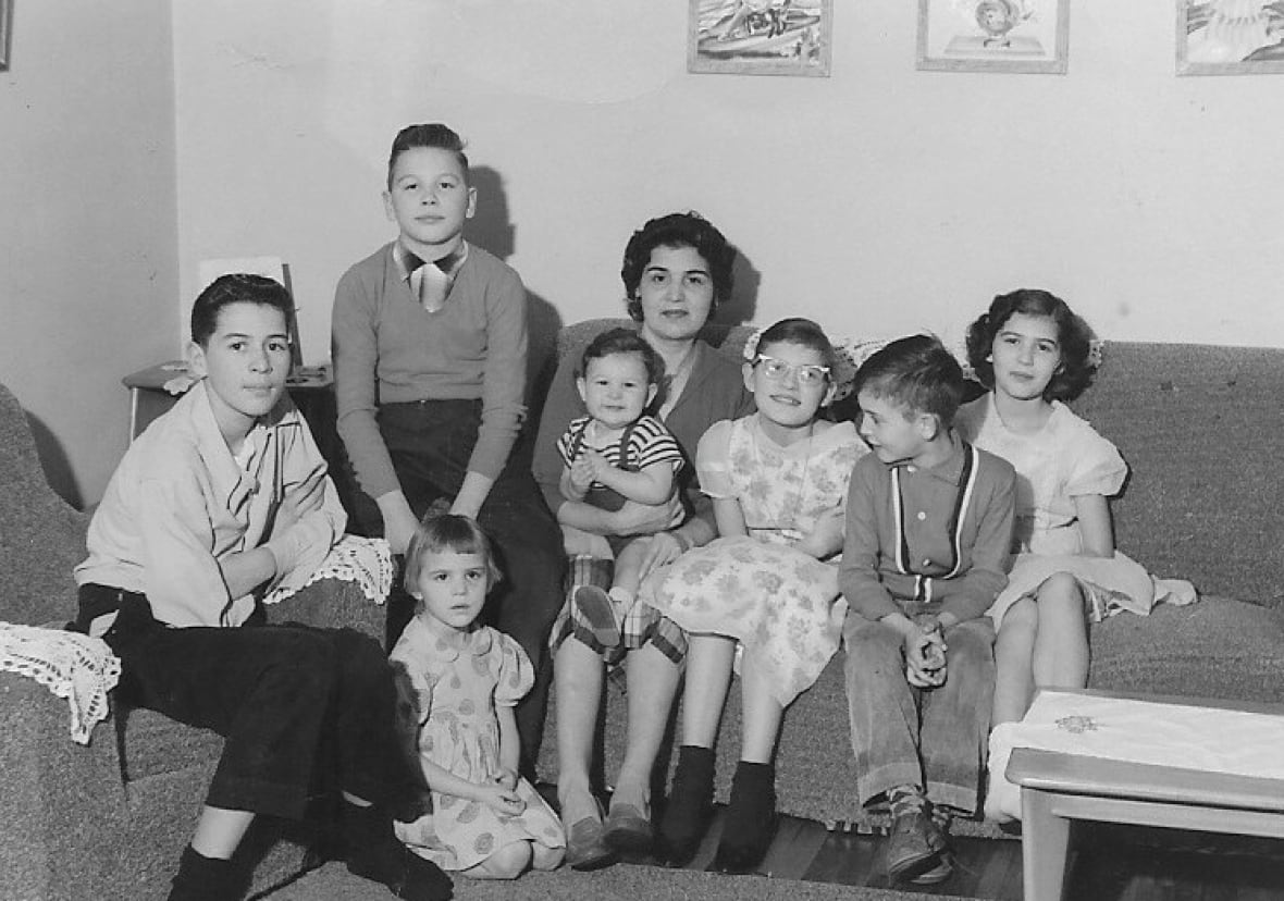 A woman on a couch surrounded by her seven children