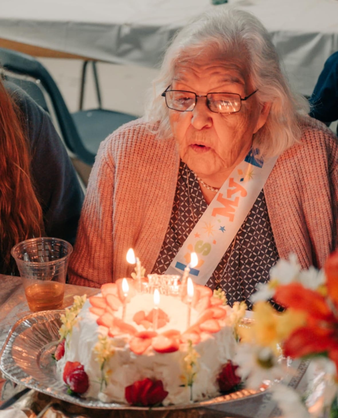 An older woman blows out birthday candles