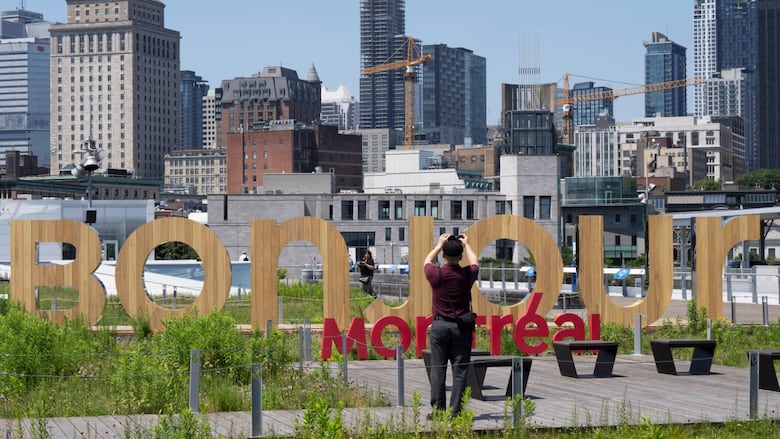 A man takes a picture of a sign that says Bonjour Montreal.
