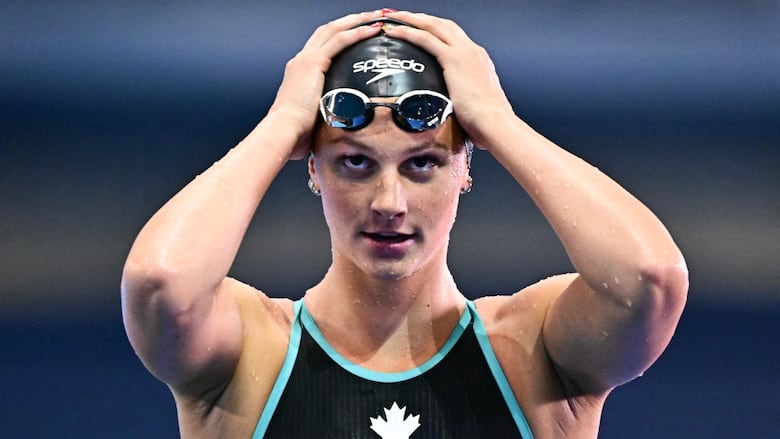 A women's swimmer adjusts her cap.
